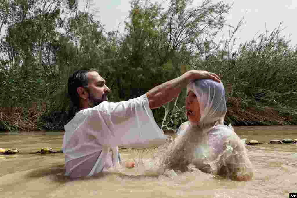 A Christian pilgrim is baptized by a priest in the muddy water of the Jordan River at the Kasser-Al-Yahud baptismal site near the West Bank city of Jericho.