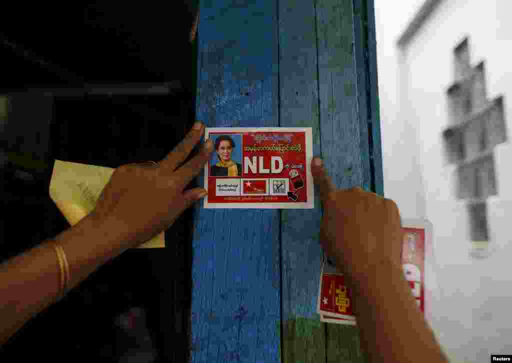A National League for Democracy (NLD) member pastes a NLD sticker in front of a voter&#39;s home as the party campaigns for the upcoming Nov. 8 general election, in Yangon, Myanmar.