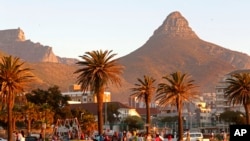 People enjoy the sunset with Table Mountain, left, and Lions Head, right, in Cape Town, South Africa.