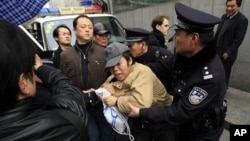 A man, center, is detained by police officers near the planned protest site is located at in Shanghai, China, February 27, 2011