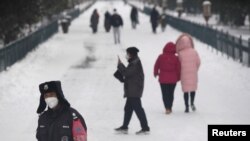 Un agente de seguridad y otras personas que pasean por el parque Tiantan de Beijing usan máscaras para protegerse del coronavirus el 6 de febrero de 2020.