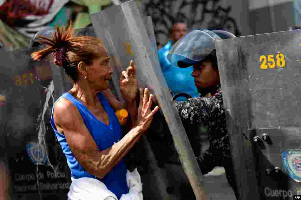 A woman confronts riot police during a protest against the shortage of food, amid Fuerzas Armadas avenue in Caracas.