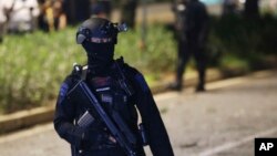 FILE - Officers stand guard at the site where an explosion that police said came from a firecracker, near the venue of the presidential candidates debate in Jakarta, Indonesia, Feb. 17, 2019. 