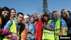 Russian President Vladimir Putin poses for a photograph with volunteers during the Olympic Winter Games in Sochi Feb. 16, 2014.