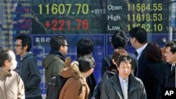 People look at an electronic stock board of a securities firm in Tokyo, Feb. 25, 2013. 