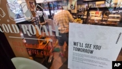 A sign advising that a Starbucks is closed, is posted in the window of a store on New York's West Side as a barista mops the floor, May 29, 2018.