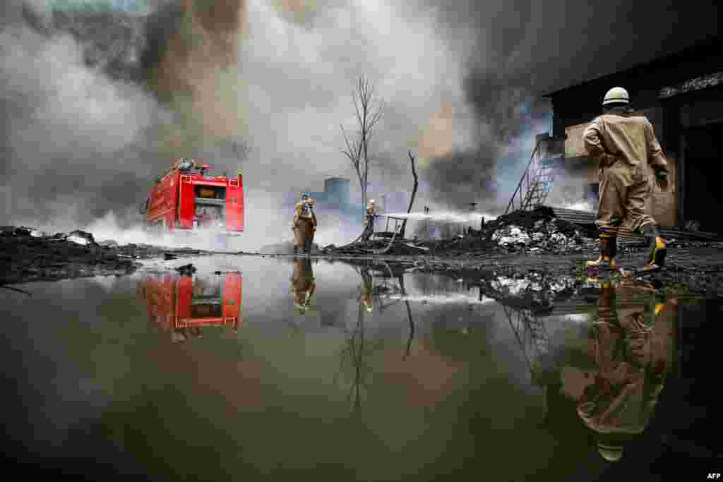 A firefighter extinguishes a fire broke out at a warehouse in New Delhi, India.