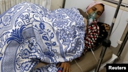 FILE - A woman, affected by what activists say was a gas attack, receives treatment inside a makeshift hospital in Kfar Zeita village in the central province of Hama May 22, 2014. 