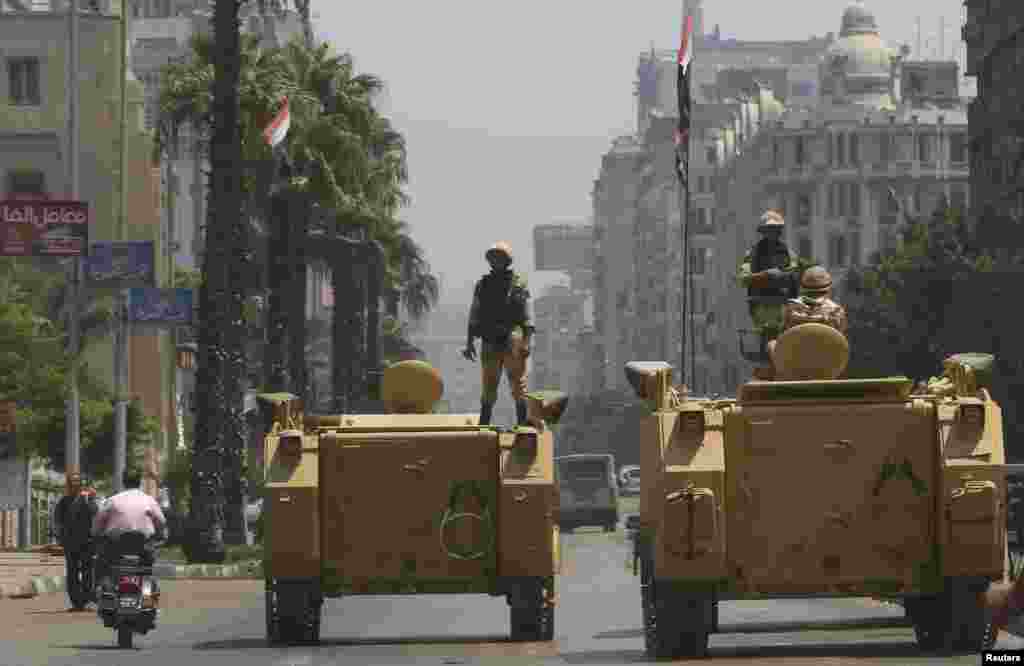A soldier holds his weapon as he stands on an armored personnel carrier positioned outside the state-run television station in Cairo, August 16, 2013. 