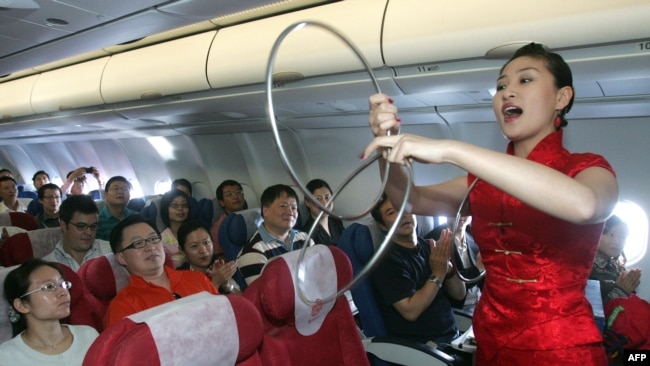 中国东方航空公司的空姐在客机上为乘客表演助兴(2007年9月26日)。