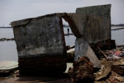 Seorang warga desa berdiri di pemecah ombak sambil memancing di pantai yang terdampak abrasi di Juntinyuat, Kabupaten Indramayu, Jawa Barat, 13 Maret 2021. (Foto: Willy Kurniawan/Reuters)