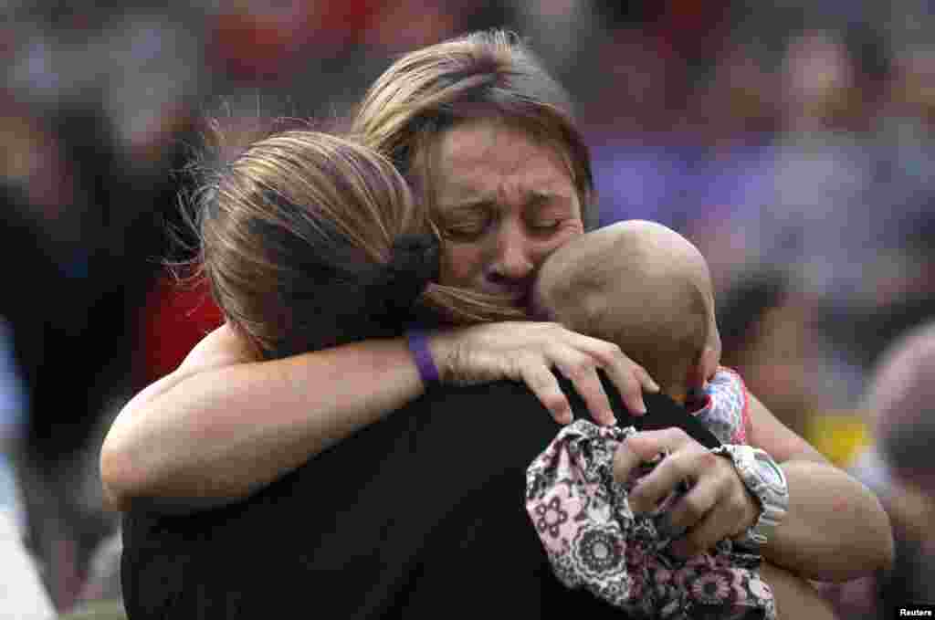 A woman holding a baby hugs another person seated in the section reserved for immediate family of the 19 firefighters killed in a nearby wildfire in Prescott, Arizona, USA, July 2, 2013. 