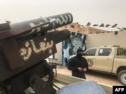 A local militiaman, belonging to a group opposed to Libyan strongman Khalifa Haftar, stands next to vehicles the group said they seized from Haftar's forces in the coastal town of Zawiya, west of Tripoli, April 5, 2019.