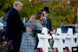 FILE - First lady Melania Trump, accompanied by President Donald Trump, and Tree of Life Rabbi Jeffrey Myers, right, puts down a white flower at a memorial for those killed at the Tree of Life Synagogue in Pittsburgh, Oct. 30, 2018.