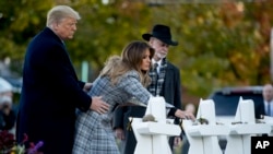 First lady Melania Trump, accompanied by President Donald Trump, and Tree of Life Rabbi Jeffrey Myers, right, puts down a white flower at a memorial for those killed at the Tree of Life Synagogue in Pittsburgh, Oct. 30, 2018.