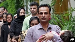 Pakistani refugees walk in line to a waiting bus after they were released from the immigration detention center in Bangkok, Thailand, June 6, 2011
