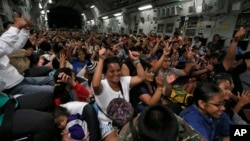 Typhoon survivors who were evacuated from Tacloban city cheer while seated onboard a U.S. military C-17 aircraft after they landed at Manila Airport, Nov. 17, 2013, in Manila, Philippines. 