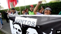 A woman shouts slogans against Peru's former president Alan Garcia outside the residence of Uruguay's ambassador to Peru, behind a sign showing an image of Garcia and Keiko Fujimori, in Lima, Peru, Nov. 18, 2018.