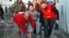 In this photo taken on Feb. 9, 2014, and released by the Syrian official news agency SANA, Syrian Arab Red Crescent members in red uniforms help evacuate an injured man on a bus out of the battleground city of Homs.