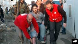 In this photo taken on Feb. 9, 2014, and released by the Syrian official news agency SANA, Syrian Arab Red Crescent members in red uniforms help evacuate an injured man on a bus out of the battleground city of Homs.