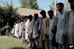 FILE - Islamic State fighters arrested by Afghan security personnel stand outside the Afghan police headquarters in Jalalabad, east of Kabul, Afghanistan, May 9, 2016.