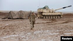 FILE - A U.S. soldier walks in front of a tank at an army base in Karamless town, east of Mosul, Iraq, Dec. 25, 2016. 