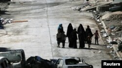 Civilians make their way next to destroyed cars in western Mosul, Iraq June 12, 2017. 