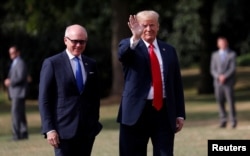 FILE - U.S. President Donald Trump waves next to U.S. Ambassador to U.K. Woody Johnson as he leaves the ambassador's residence, in London, July 13, 2018.