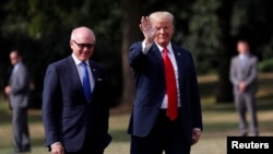 U.S. President Donald Trump waves next to U.S. Ambassador to U.K. Woody Johnson as he leaves the ambassador's residence, in London, July 13, 2018.