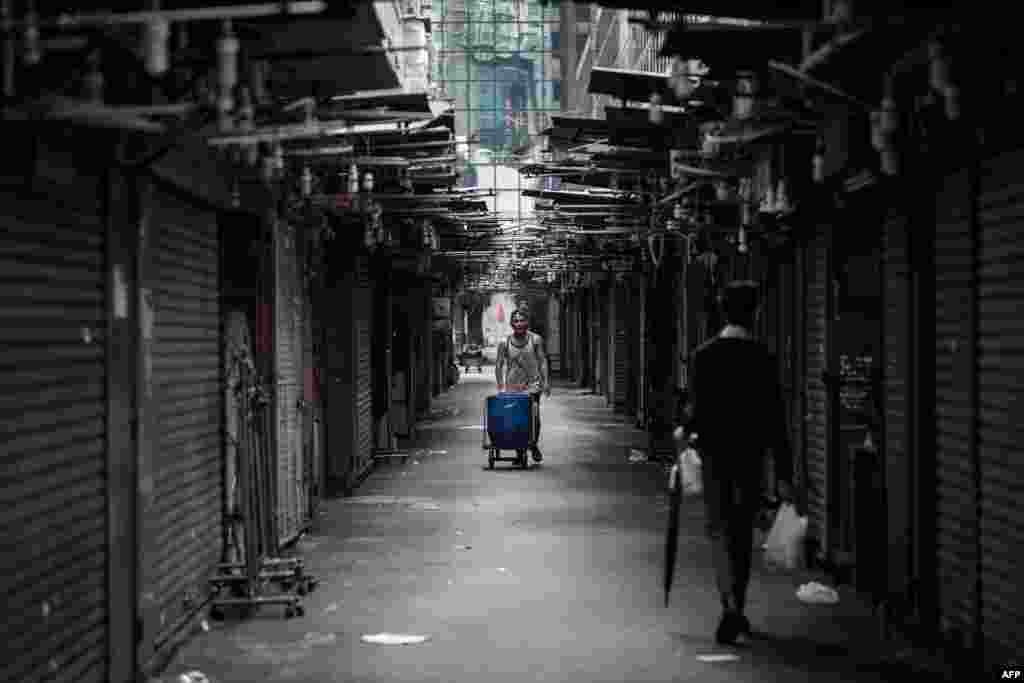 Một người đàn ông đẩy chiếc xe tay trong một chợ ven đường phố tại  Hong Kong. Loại xe tay kiểu cổ này giúp thành phố này vận chuyển.