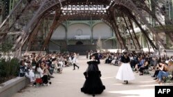 FILE - Models present creations for Chanel under a replica of the Eiffel Tower at the Grand Palais during the 2017-2018 fall/winter Haute Couture collection in Paris, July 4, 2017. 