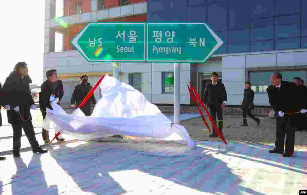 북한 개성 판문역에서 열린 '경의선·동해선 철도·도로 연결 및 현대화 착공식'에서 남·북 고위관리들이 서울과 평양을 가리키는표지판을 덮은 천을 벗기고 있다.