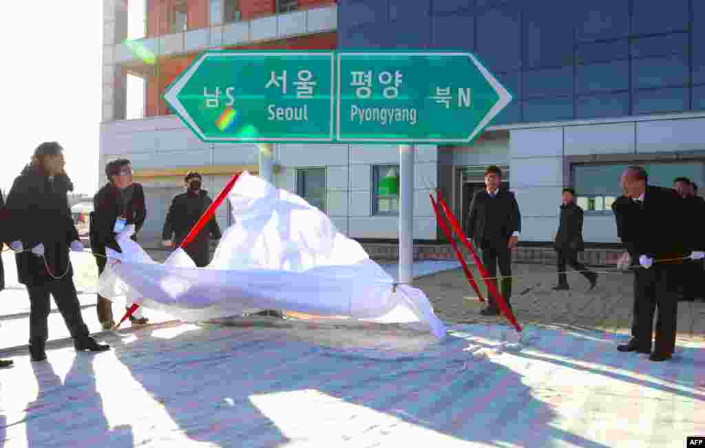 북한 개성 판문역에서 열린 &#39;경의선&middot;동해선 철도&middot;도로 연결 및 현대화 착공식&#39;에서 남&middot;북 고위관리들이 서울과 평양을 가리키는표지판을 덮은 천을 벗기고 있다.