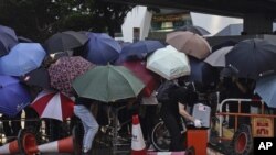 形成路障阻挡香港道路的抗议者躲在遮阳伞后面。（美联社2019年10月4日）