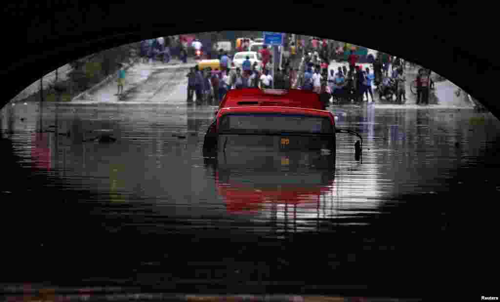A bus is seen submerged on a flooded road under a railway bridge after heavy rains in New Delhi, India.
