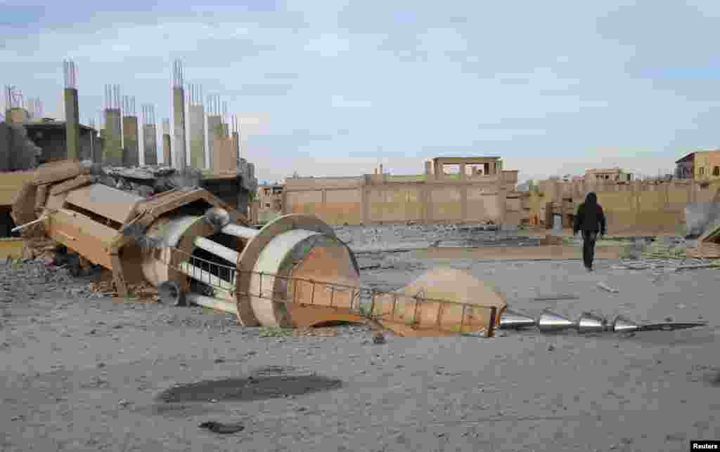 A man walks past a damaged mosque after what activists said were airstrikes by forces loyal to Syria's President Bashar al-Assad in Raqqa, eastern Syria, which is controlled by the Islamic State, Nov. 25, 2014.