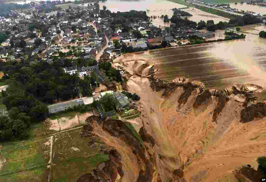 Rescuers hurry to help people trapped in their homes in the town of Erftstadt, southwest of Cologne. Images like this one provided by the Cologne district government show what appears to be a massive sinkhole.