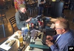 Joe Van Cleave, left, and Rich Boucher try out various vintage typewriters at a "type-in" in Albuquerque, N.M., April 23, 2017.