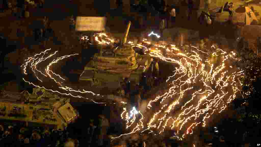 معترضان ضد دولتی که شمع بدست دارند یک تانک نیروهای ضد شورش مصر را در میدان تحریر شهر قاهره احاطه کرده اند