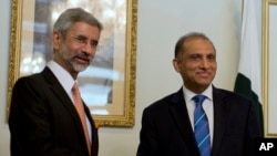 Indian Foreign Secretary Subrahmanyan Jaishankar, left, poses for photographers, as he shakes hands with his Pakistani counterpart Aizaz Chaudhry at the foreign ministry in Islamabad, Pakistan, Tuesday, March 3, 2015.