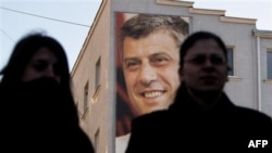 Жительницы Косово на фоне постера с изображением премьер-министра Хашима Тачи