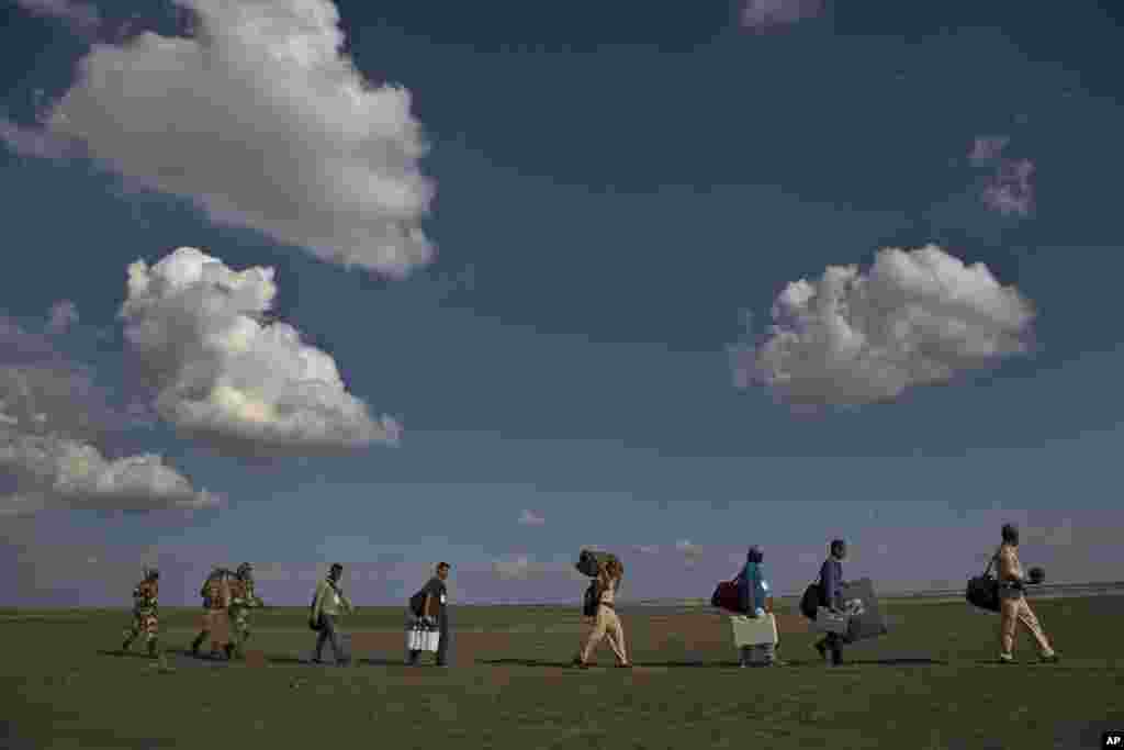 Paramilitary soldiers guard election officials carrying election materials as they travel along the Brahmaputra River so they can board a boat on the eve of the first phase of general elections in Majuli, Assam, India.