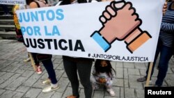 La gente sostiene una pancarta que dice "Juntos por la justicia" durante una protesta contra el gobierno del presidente venezolano Nicolás Maduro antes de la llegada al país del Fiscal de la Corte Penal Internacional, Karim Khan, en Caracas, el 29 de octubre de 2021.