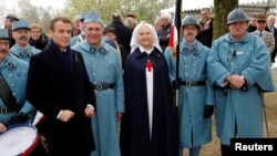 French President Emmanuel Macron poses with history enthusiasts, dressed with vintage army uniforms as Poilu (French World War I soldiers), after a ceremony at the Memorial to the Battle of Morhange, Eastern France, Nov. 5, 2018.