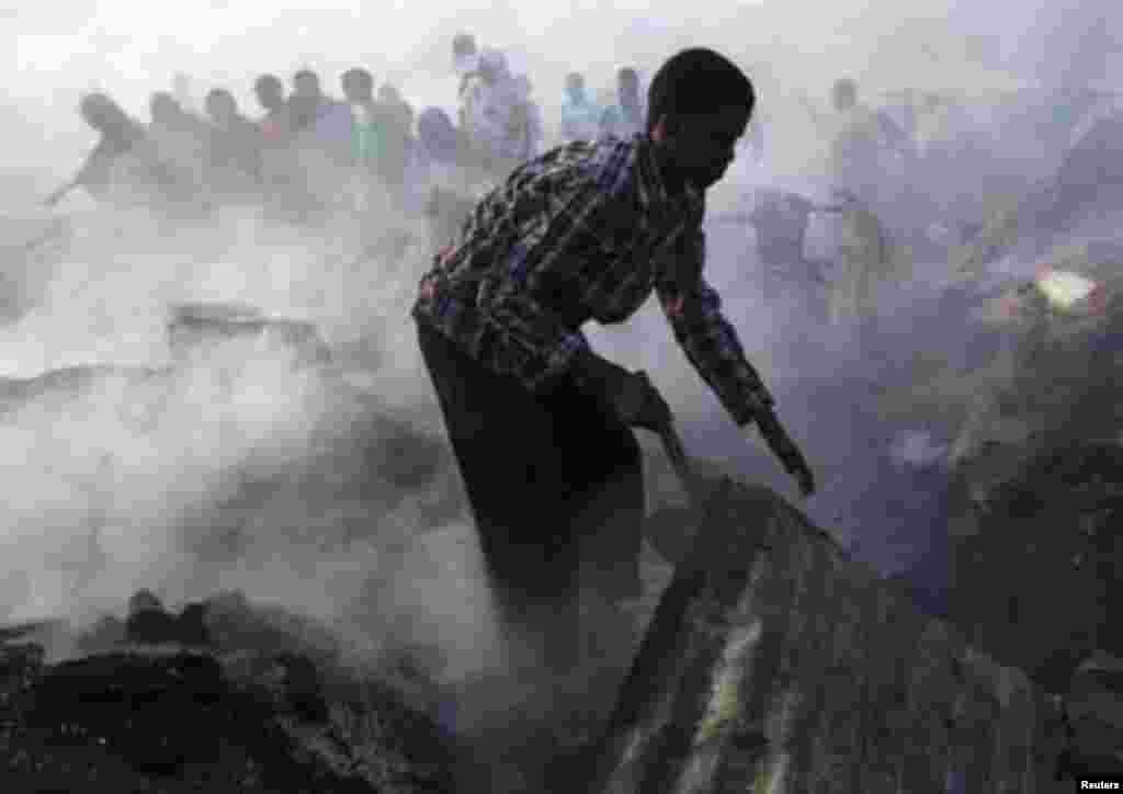 A man stands near debris at the scene of a fire that razed an entire market in Hamaerweyne district south of capital Mogadishu January 26, 2012. REUTERS/Feisal Omar (SOMALIA - Tags: DISASTER ENVIRONMENT BUSINESS)