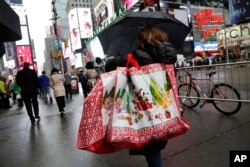 FILE - A woman walks through Times Square with holiday shopping bags, Dec. 2, 2015, in New York.