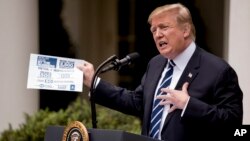 President Donald Trump holds up a stat sheet having to do with the Mueller Report as he speaks in the Rose Garden at the White House, May 22, 2019.