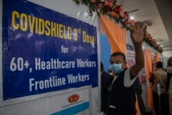 Seorang pria lansia India melambaikan tangan ke kamera sebelum divaksin dosis ketiga COVID-19 di sebuah rumah sakit pemerintah di Gauhati, India, Senin, 10 Januari 2022.