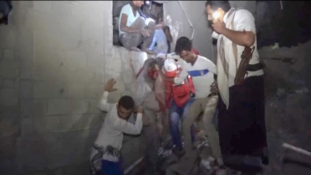 An image provided by Al-Masirah TV on Jan. 21, 2022, shows Yemenis rescuing a man from a site following Saudi-led airstrikes on Yemen's rebel-held port city of Hodeidah.