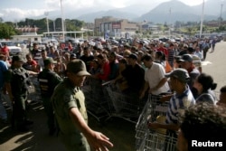 National guards control the entrance of a private supermarket as people line up to enter in San Cristobal, Jan. 15, 2015.